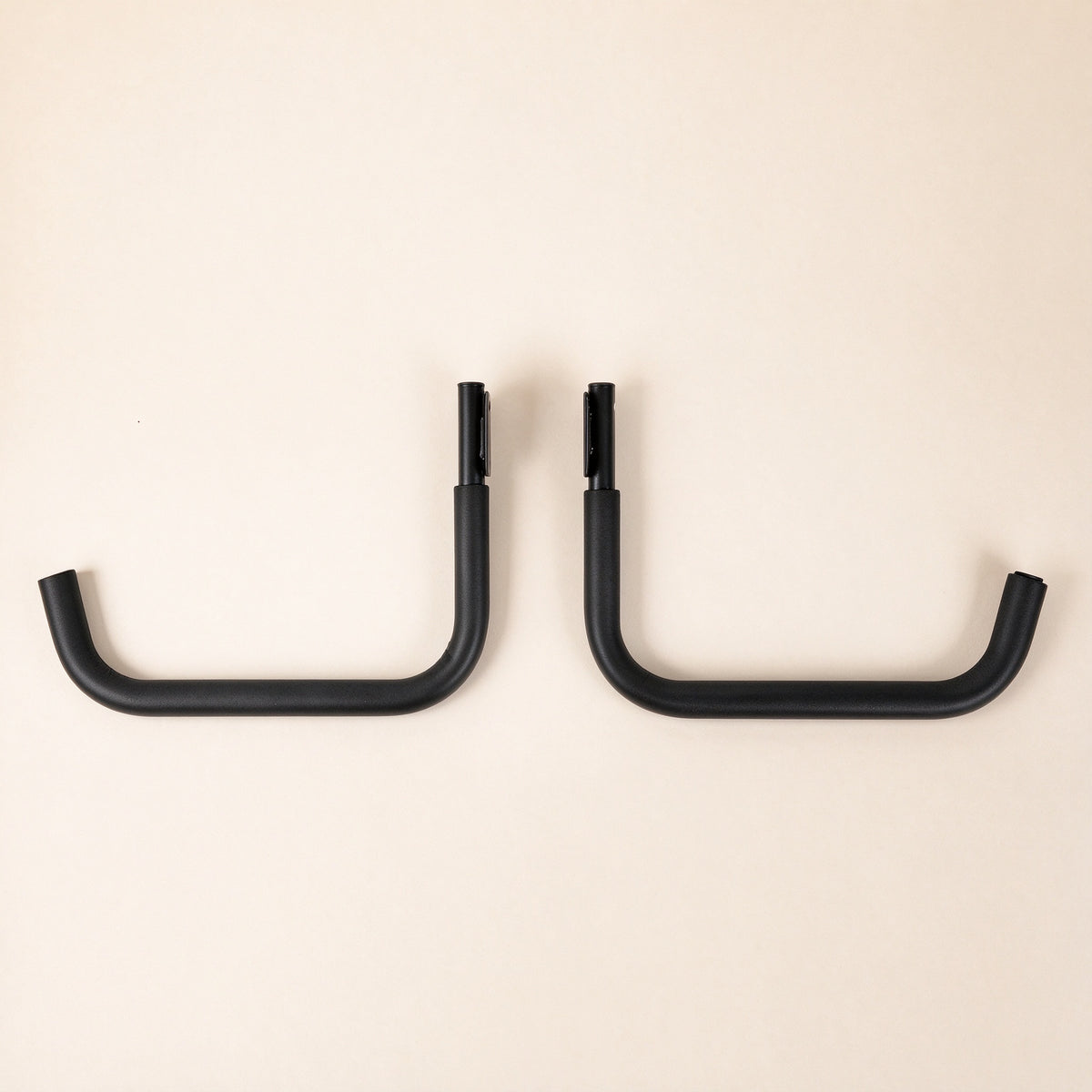 Pair of black J-shaped kayak wall hooks with foam sleeves on the arms, product only on a cream background